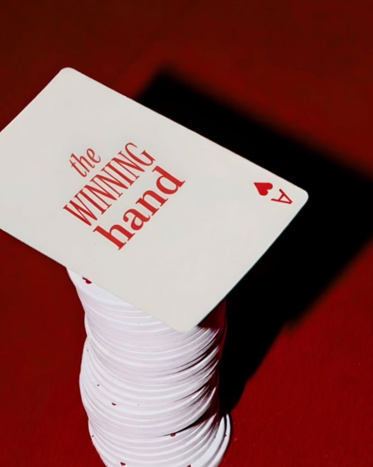 Un as de corazones sobre una torre de fichas blancas en un paño rojo